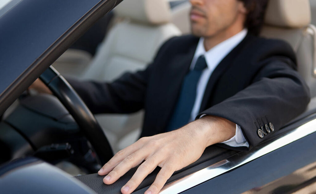 a man driving a car, with his hand resting on the door